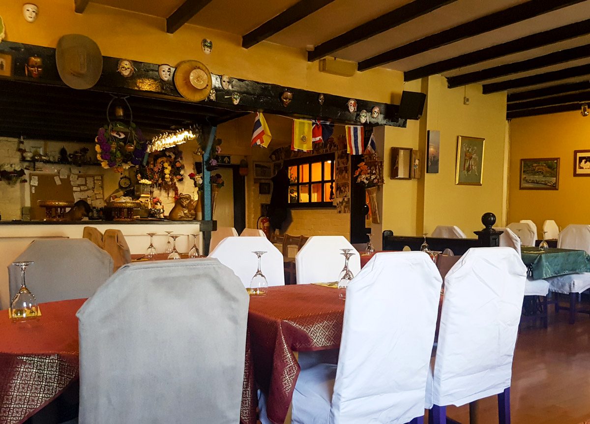 The dining room: yellow walls, dark wooden beams, red tablecloths and chairs in white covers