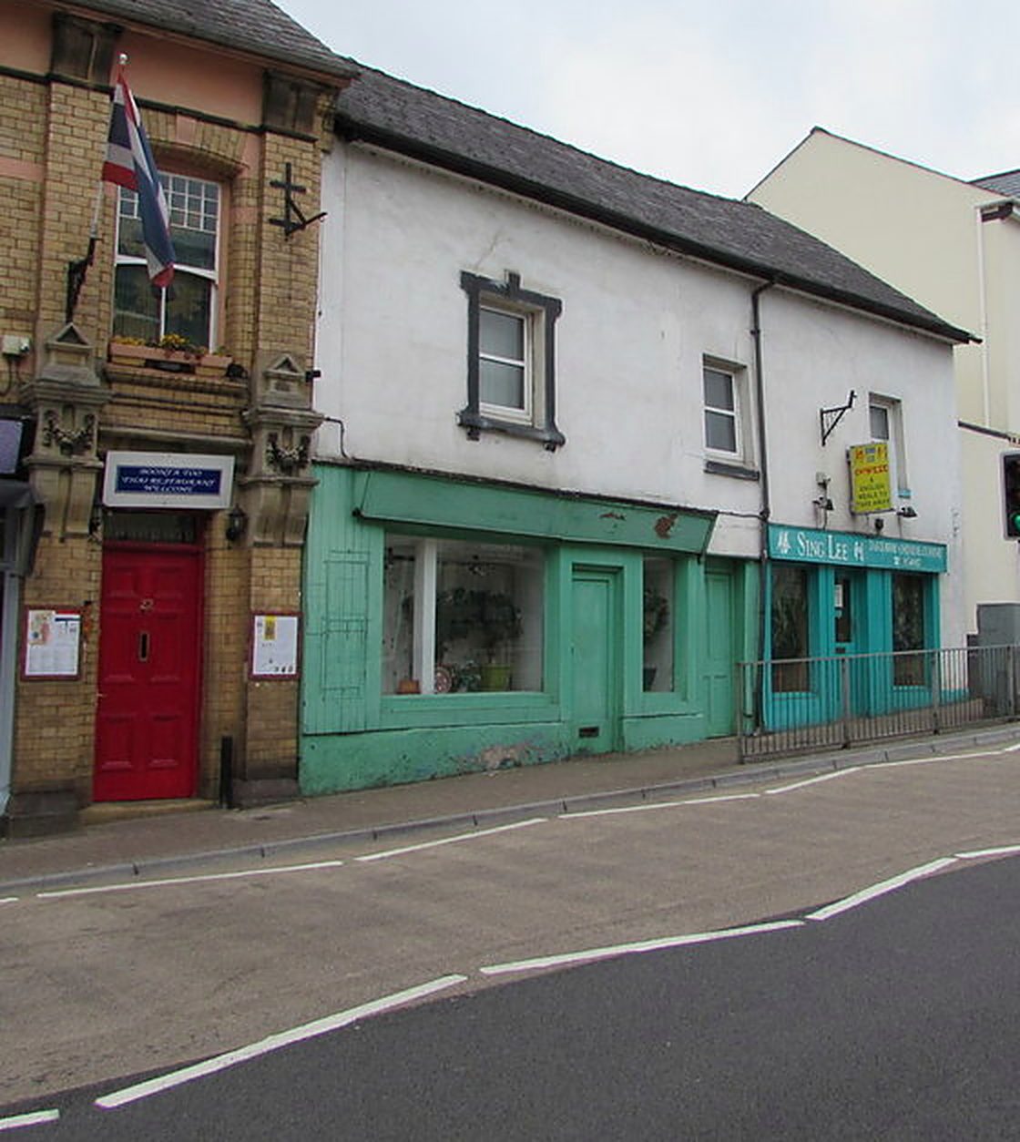 Cross Street, Abergavenny: a brick building with a red front door beside a shop with a green front